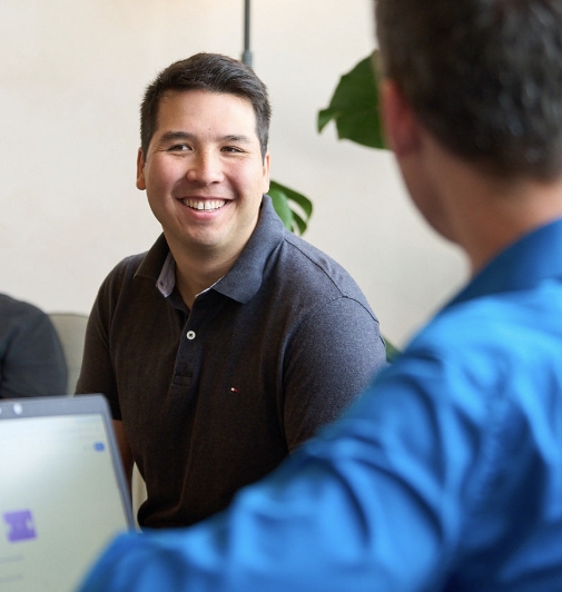 Collègue souriant en discussion dans un bureau avec un ordinateur portable