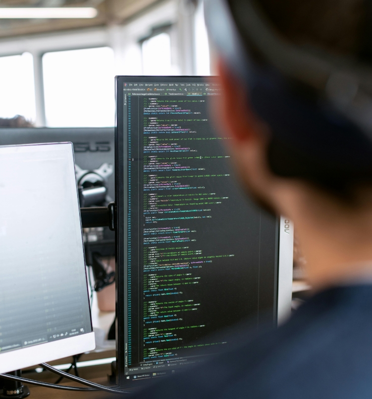 Développeur informatique devant deux écrans affichant du code de programmation